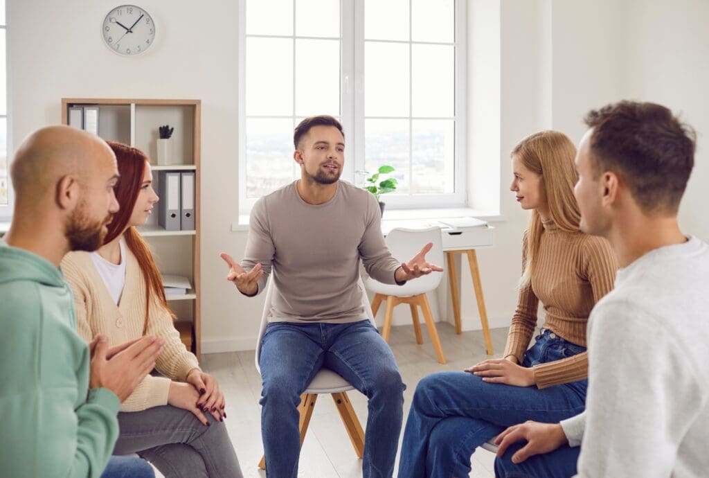 Eine Gruppe von fünf Personen sitzt im Kreis und führt eine Diskussion über Angewandte Psychologie.