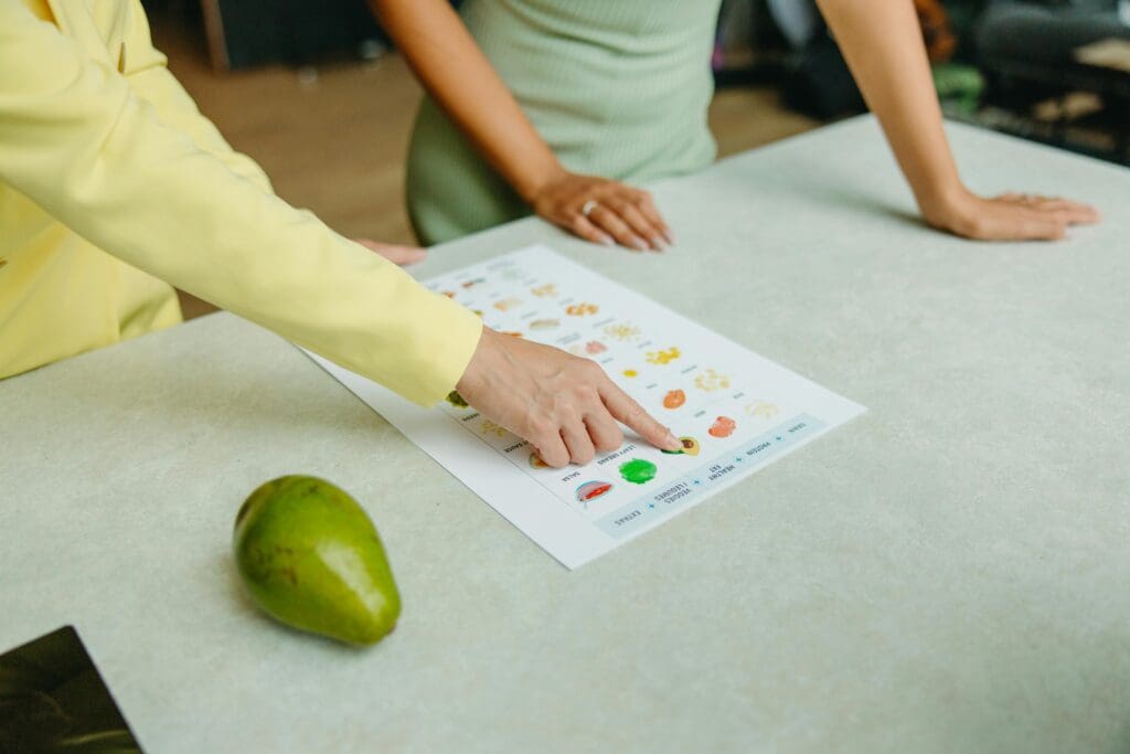 Zwei Studierende der Gesundheitspsychologie besprechen ein Diagramm. Im Vordergrund liegt eine Birne.